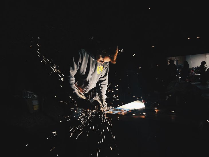 Highlander Racing student fabricating metal in the workshop with sparks flying